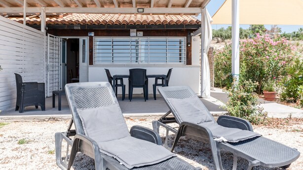 A covered outdoor seating area with lounge chairs, a table, and chairs. - Holiday Home 'Abbacari 1' with Sea View, Wi-Fi and Air Conditioning (Realmonte)