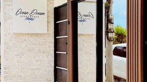 Entrada de un edificio con un cartel que dice 'Ocean Dream Apartments I' y un letrero de advertencia sobre cámaras de seguridad.