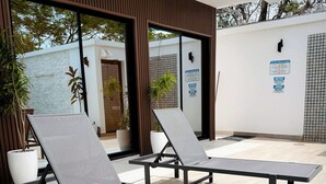 Un espacio al aire libre moderno con dos sillones, una planta en maceta y una pared con un letrero.