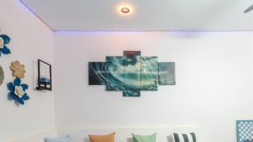 Una habitación con una obra de arte colgada en la pared que representa una escena marina y una lámpara en el techo.