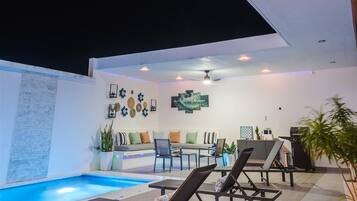 Un área de piscina interior moderna con sillones de descanso, un sofá y un comedor.