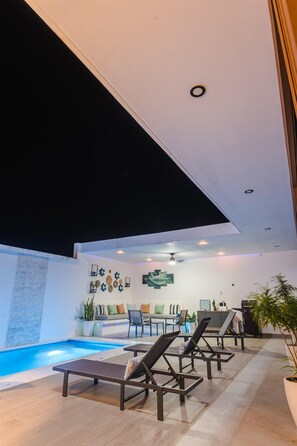 A modern indoor pool area with lounge chairs, a sofa, and a dining area. - Ocean Dream Apartments E1-A1 (San Juan del Sur)