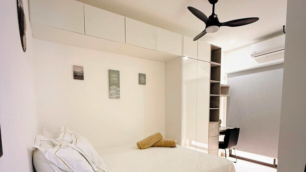 Un dormitorio con cama, ventilador de techo y armario.
