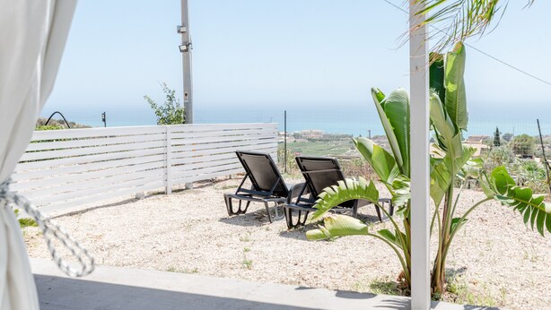 A patio with two lounge chairs, a white fence, and a view of the ocean. - Holiday Home 'Abbacari 2' with Sea View, Wi-Fi and Air Conditioning (Realmonte)
