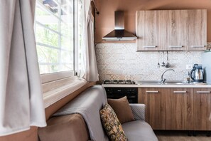 A compact kitchen with a gas stove, wooden cabinets, and a patterned backsplash.