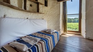 Une pièce rustique avec un banc en bois, un coussin blanc et une vue sur la verdure par la fenêtre.