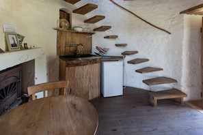A rustic kitchen with wooden cabinets, a white refrigerator, and a dining table.