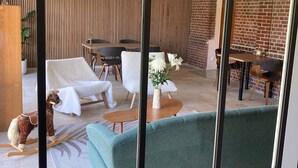 Una sala de estar moderna con un ventanal grande, un comedor con pared de ladrillo y una zona de estar acogedora con un sofá verde.