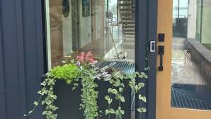 A modern building entrance with a glass door, a staircase, and a planter with green plants. - Lake Minnetonka Retreat (Mound)