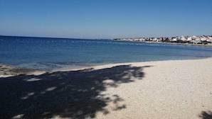 A beach with clear blue water, a sandy shore, and a row of buildings in the background. - Spacious seaside villa, Private Pool &Parking,5 bedrooms,Sea View,Diklo,Zadar (Zadar)