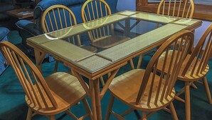 Une table à manger avec quatre chaises, un plateau en verre et un coussin d’assise en tissu tissé.