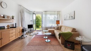 En moderne stue med sofa, sofabord, fjernsyn og et glashus.