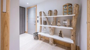 A hallway with wooden shelves displaying rustic decor items, a grey door, and a light-colored floor. - Renovated apartment for 5 - with balcony (Megève)