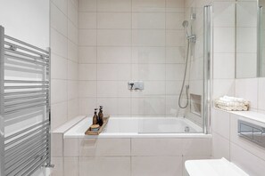 A modern bathroom with a glass-enclosed shower, a white bathtub, and a towel rack. - London Road Apartment in Isleworth (Isleworth)
