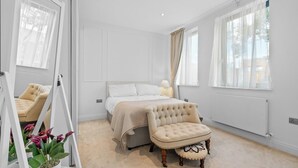 A bedroom with a bed, bedside table, lamp, chair, and potted plant. - London Road Apartment in Isleworth (Isleworth)