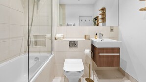 A modern bathroom with a glass-enclosed shower, a white toilet, and a vanity with a sink and mirror. - London Road Apartment in Isleworth (Isleworth)
