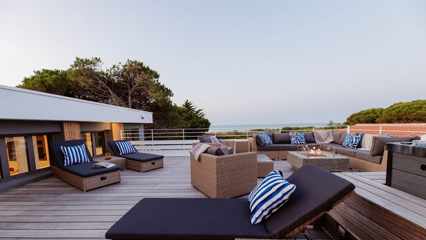 A rooftop deck with outdoor seating, including sofas and chairs, and a fire pit.