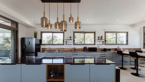 A modern kitchen with a central island, pendant lighting, and large windows.