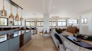 A spacious kitchen with a central island, large windows, and a modern dining area with a sofa and coffee table.