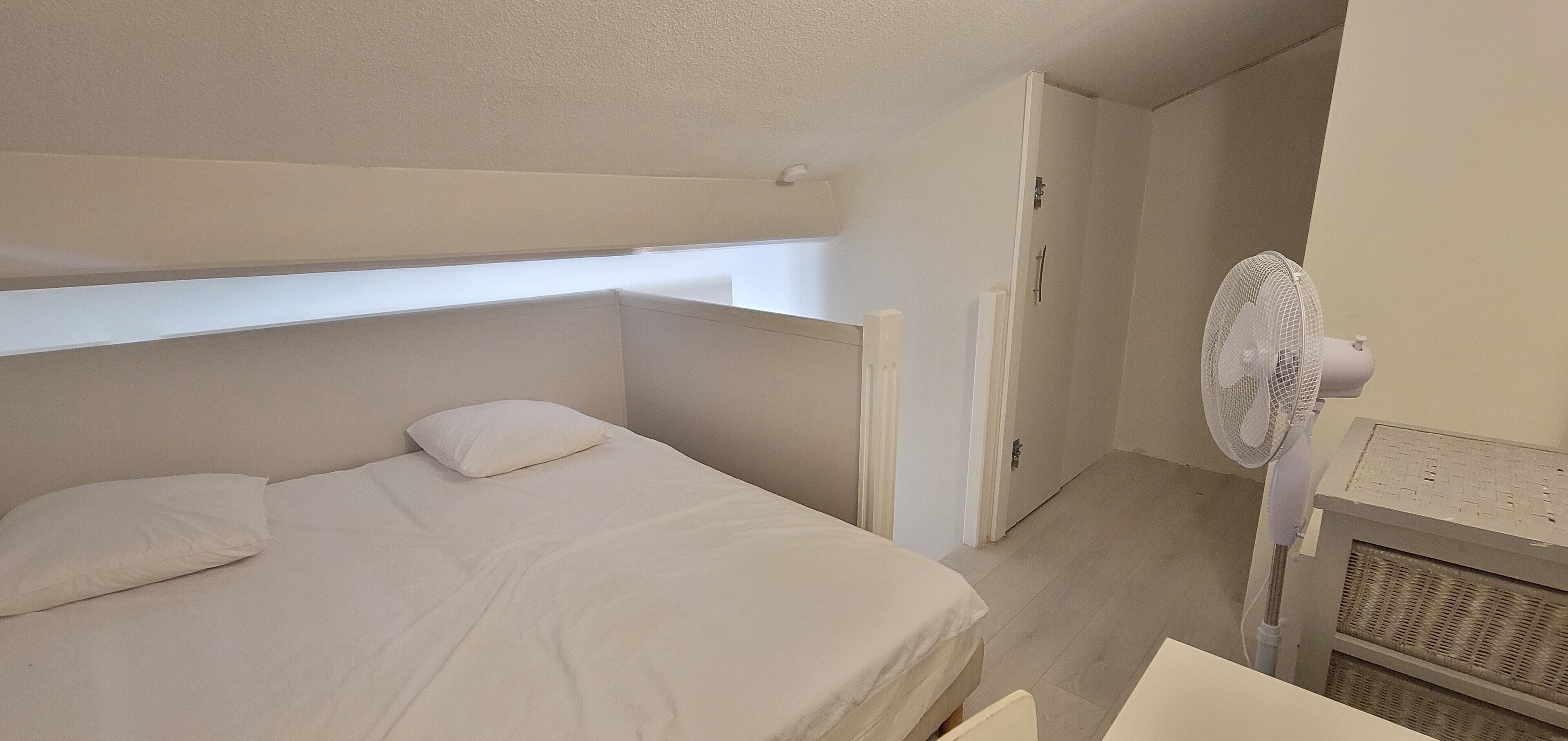 Un dormitorio con literas, un ventilador de pie y un radiador.