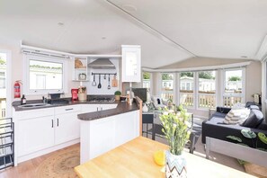 Een moderne keuken met witte kastjes, een centraal eiland en een eethoek met een houten tafel.