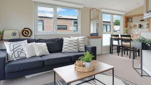 A modern living room with a sofa, coffee table, and dining area. - The Chester-2 bed Static Caravan (Jedburgh)