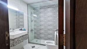 Ein modernes Badezimmer mit Duschkabine aus Glas, einem weißen Waschbecken und einer Toilette.
