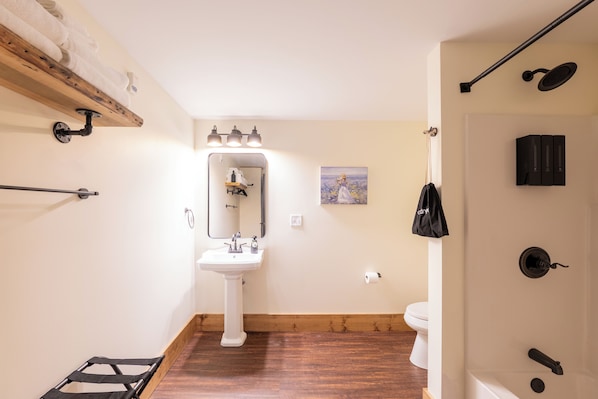 A bathroom with a wooden floor, white sink, and a shower area. - The Tanglewood (Versailles)