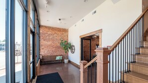 Ein geräumiger Innenraum mit Backsteinwand, einer Holztreppe und einem großen Fenster mit Blick ins Freie.