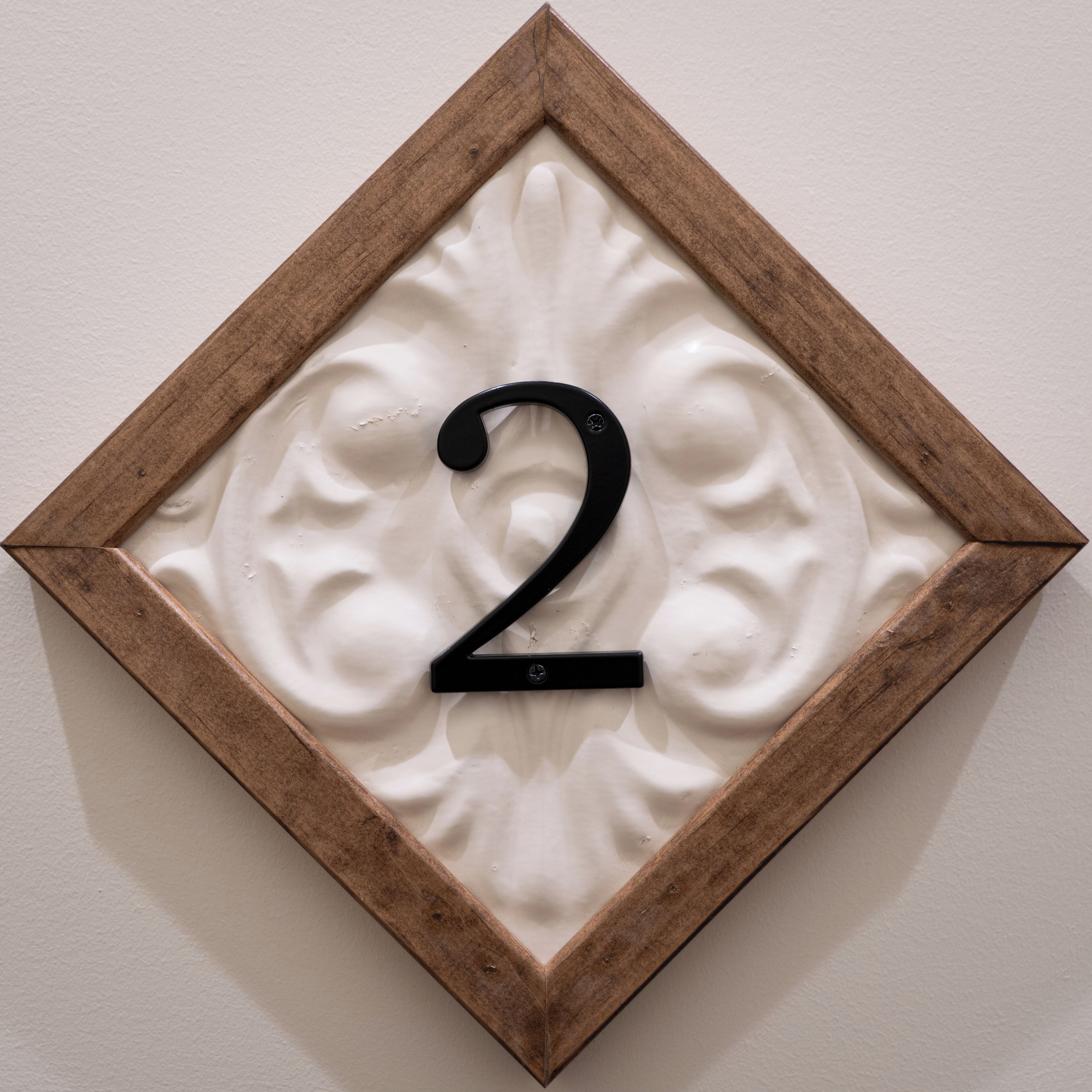 A wall-mounted number '2' sign with a wooden frame and a textured background.