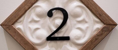 A wall-mounted number '2' sign with a wooden frame and a textured background.