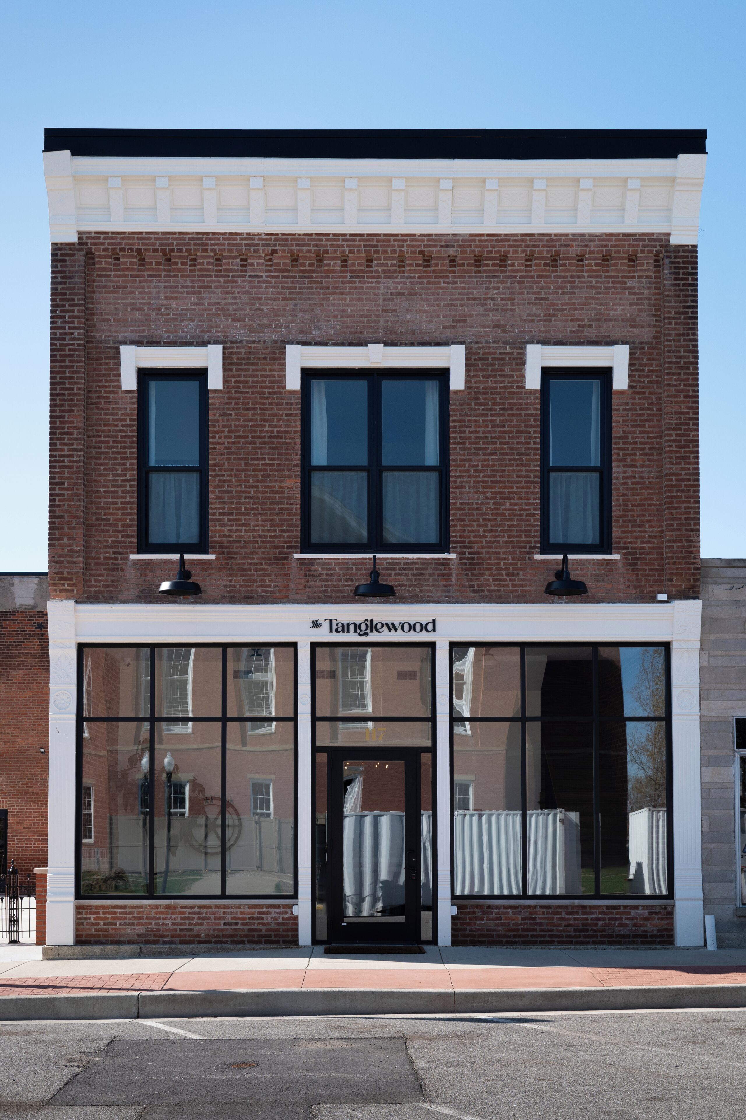 A two-story brick building with large windows and a sign reading "Tangwood."