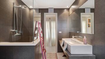 A modern bathroom with a glass shower enclosure, a white sink, and a large mirror.