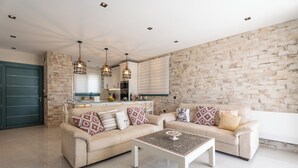 Een moderne woonkamer met twee beige banken, een salontafel en een keuken op de achtergrond.