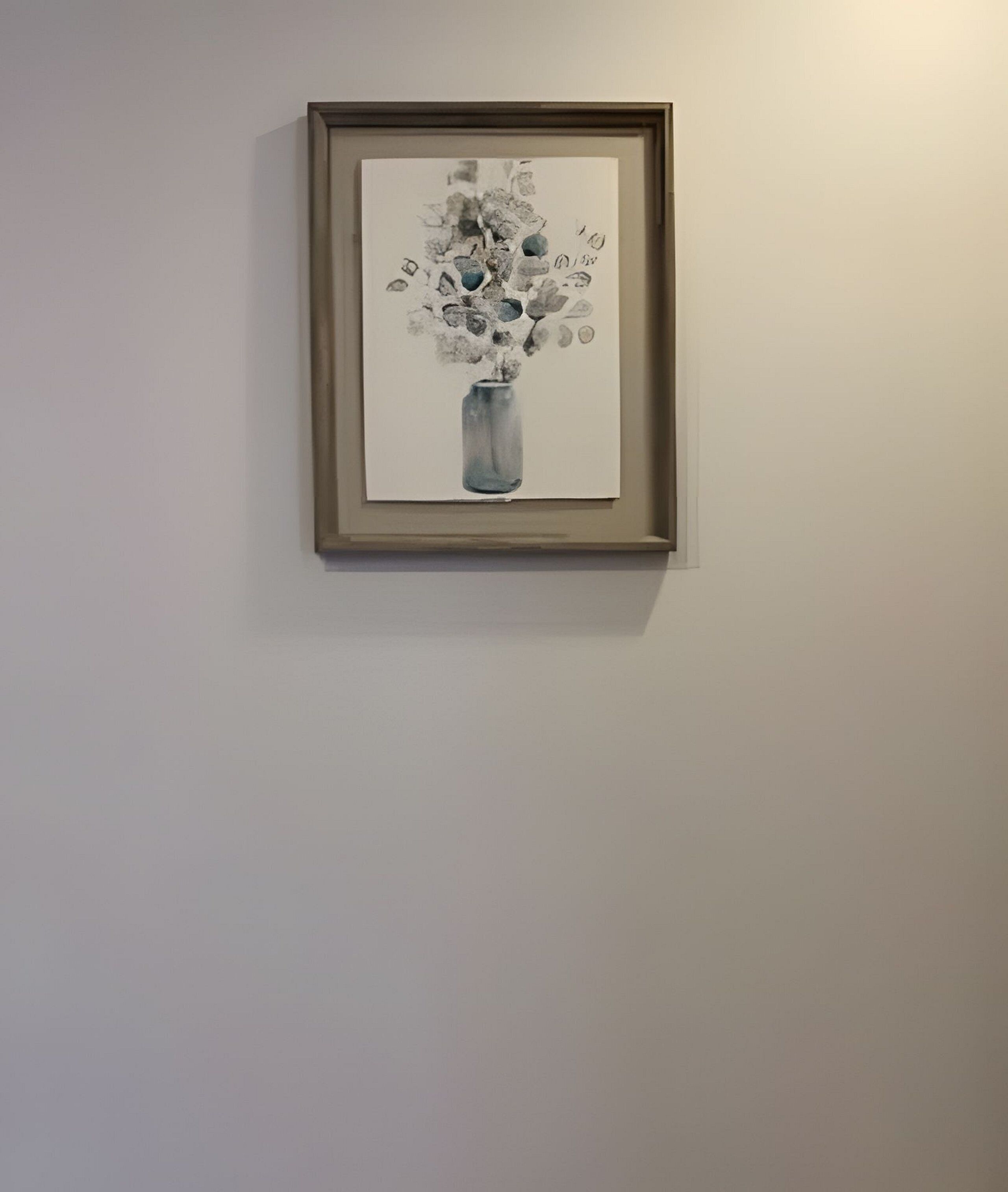 A framed artwork of a vase with flowers on a plain wall.