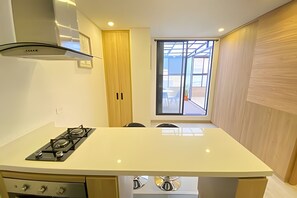 A modern kitchen with a gas stove, a built-in oven, and a window with a view of the outside. - Edificio Benyalt 94 (Bogota)
