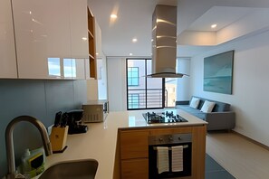 A modern kitchen with a central island, built-in cabinets, a large window, and a seating area with a sofa. - Edificio Benyalt 94 (Bogota)