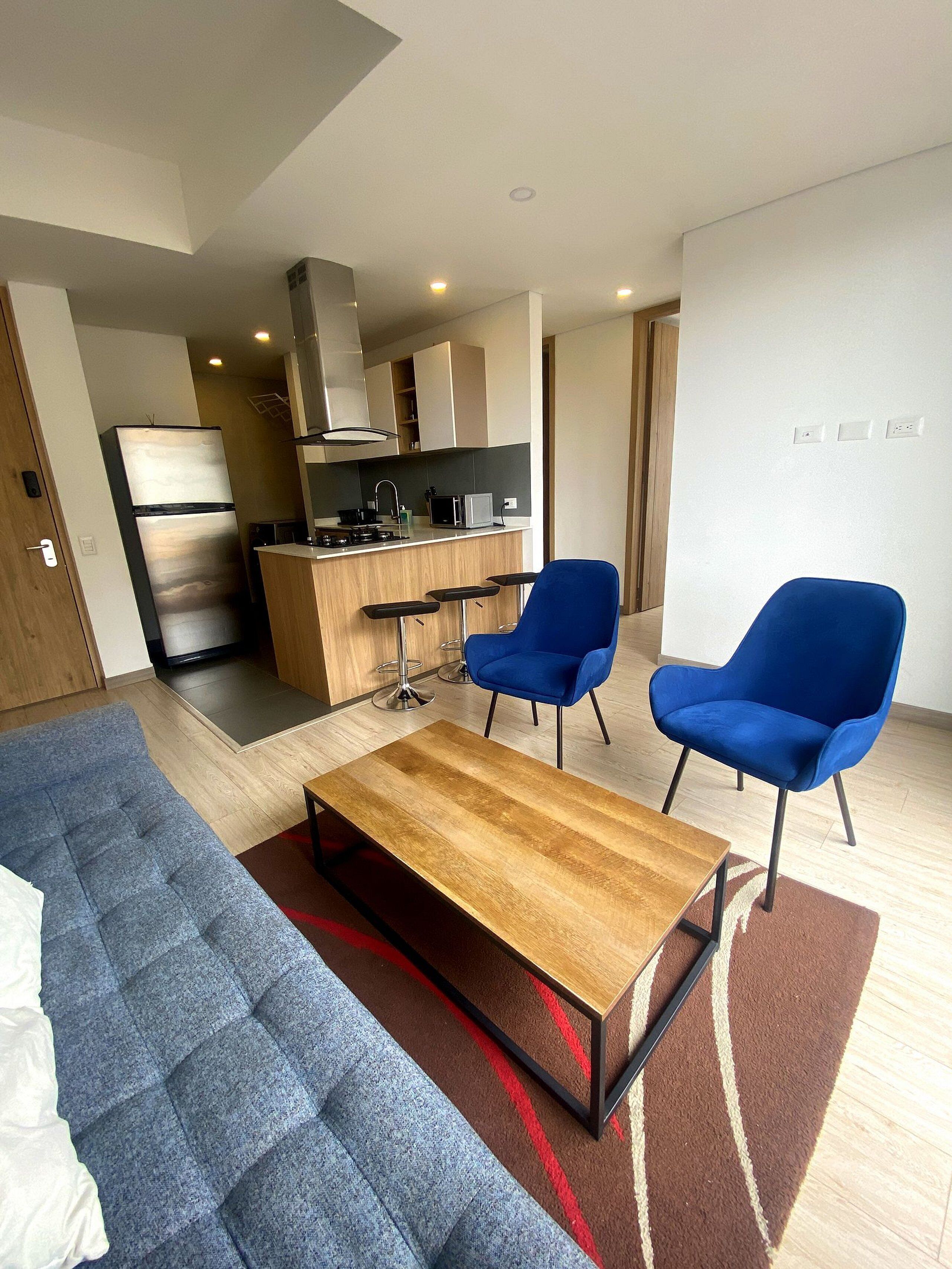 Un salon moderne avec un canapé, une table basse et deux fauteuils bleus.