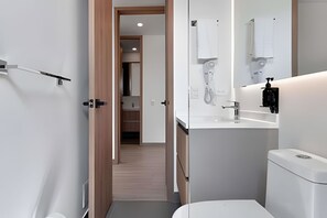 Un baño moderno con inodoro, lavamanos y espejo.
