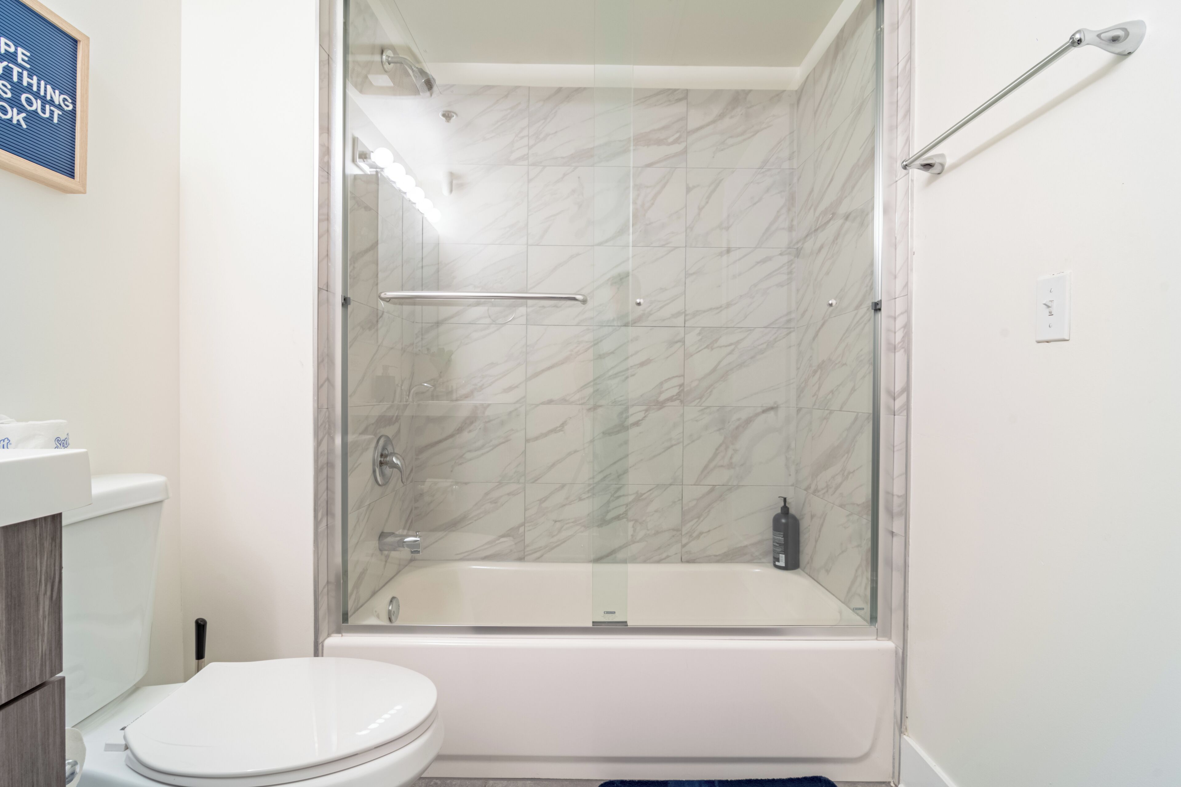 A bathroom with a glass-enclosed shower, a white bathtub, and a toilet.