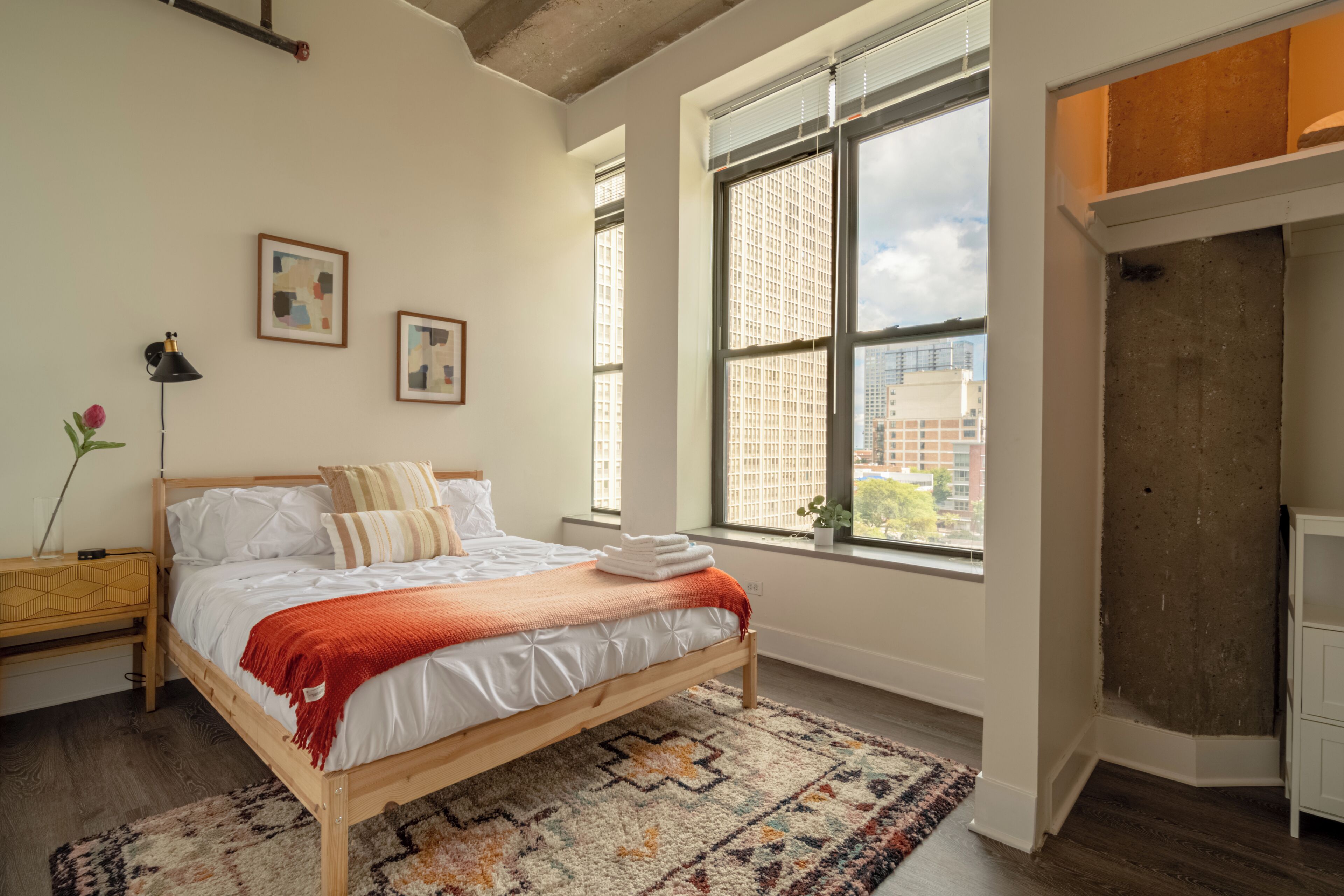 Ein Schlafzimmer mit einem großen Bett, einem Fenster mit Blick auf die Stadt und einem Holzboden.