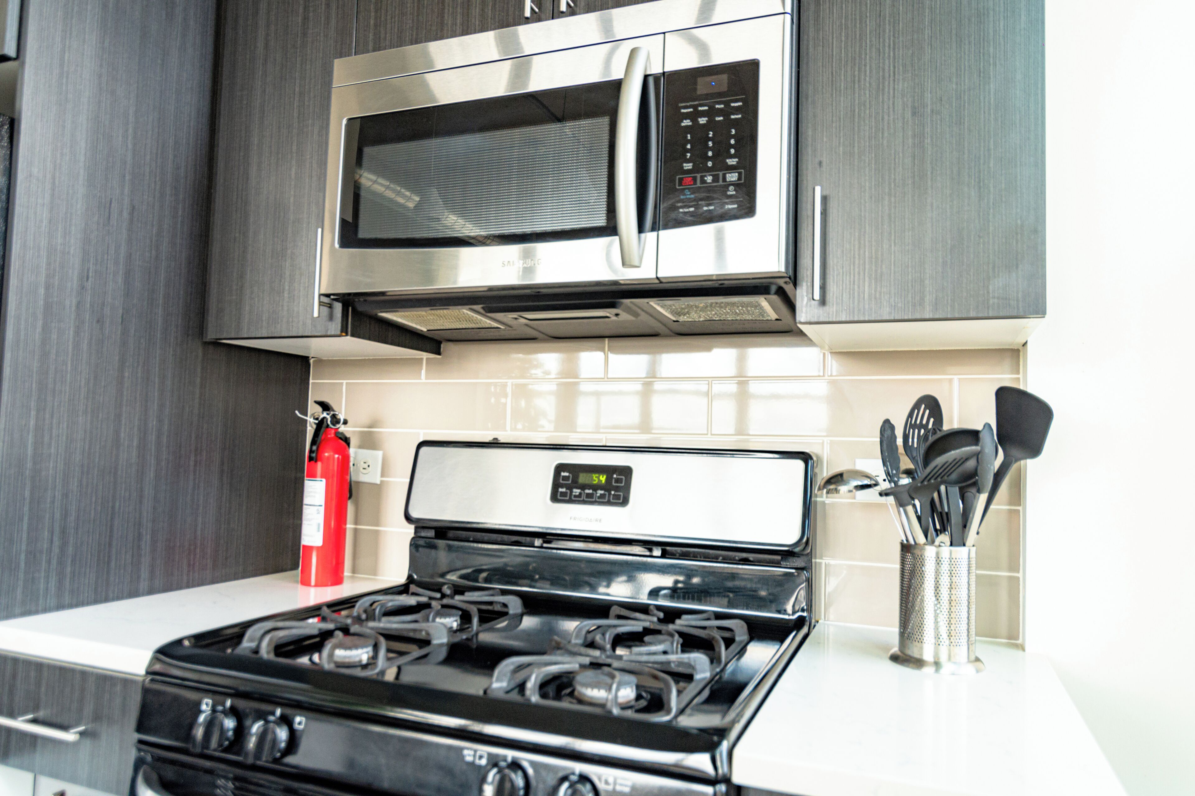 A kitchen with a stainless steel stove, a microwave, and a fire extinguisher.