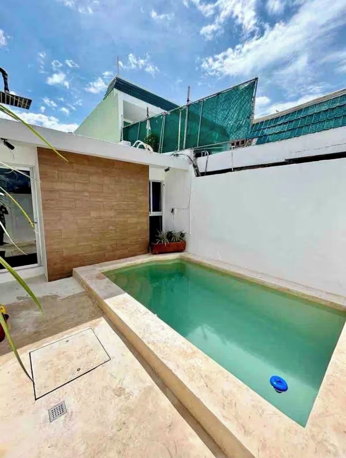A swimming pool with a wooden deck and a small garden area.