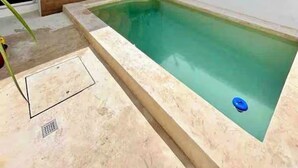 A swimming pool with a wooden deck and a small garden area.