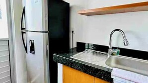 A compact kitchen with a built-in refrigerator, a sink, and wooden cabinets.