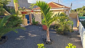 Ein Haus mit Ziegeldach, umgeben von Kies, Blumentöpfen und einem kleinen Garten.