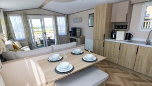 Eine moderne Küche mit Holzausstattung, einem Essbereich mit einer Bank und einem Blick ins Freie durch große Fenster.