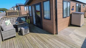 Eine Holzhütte mit einer Terrasse, ausgestattet mit einer Couch und einem Tisch.