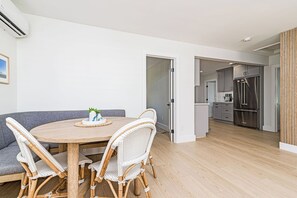 Eine moderne Küche mit Edelstahlgeräten und einem Essbereich mit Korbstühlen und einem Holztisch.
