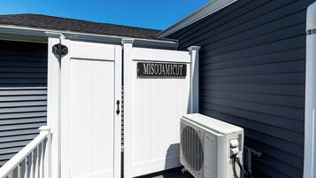 A white outdoor unit with a sign reading "MISQUAMICUT" attached to a building with dark siding.